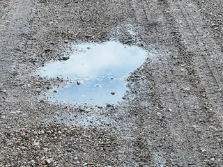 Photograph: standing water lying on the stone surface of a site road