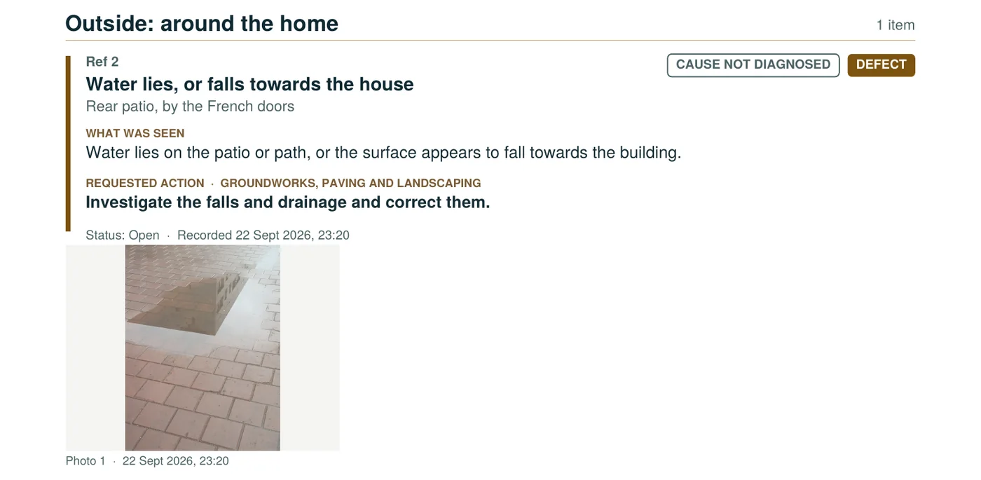 Part of a HOME report page: Outside, around the home. Ref 2, Water lies, or falls towards the house, at the rear patio by the French doors. What was seen, the requested action for groundworks, paving and landscaping, marked cause not diagnosed, status open, and a photograph of water lying on the patio.